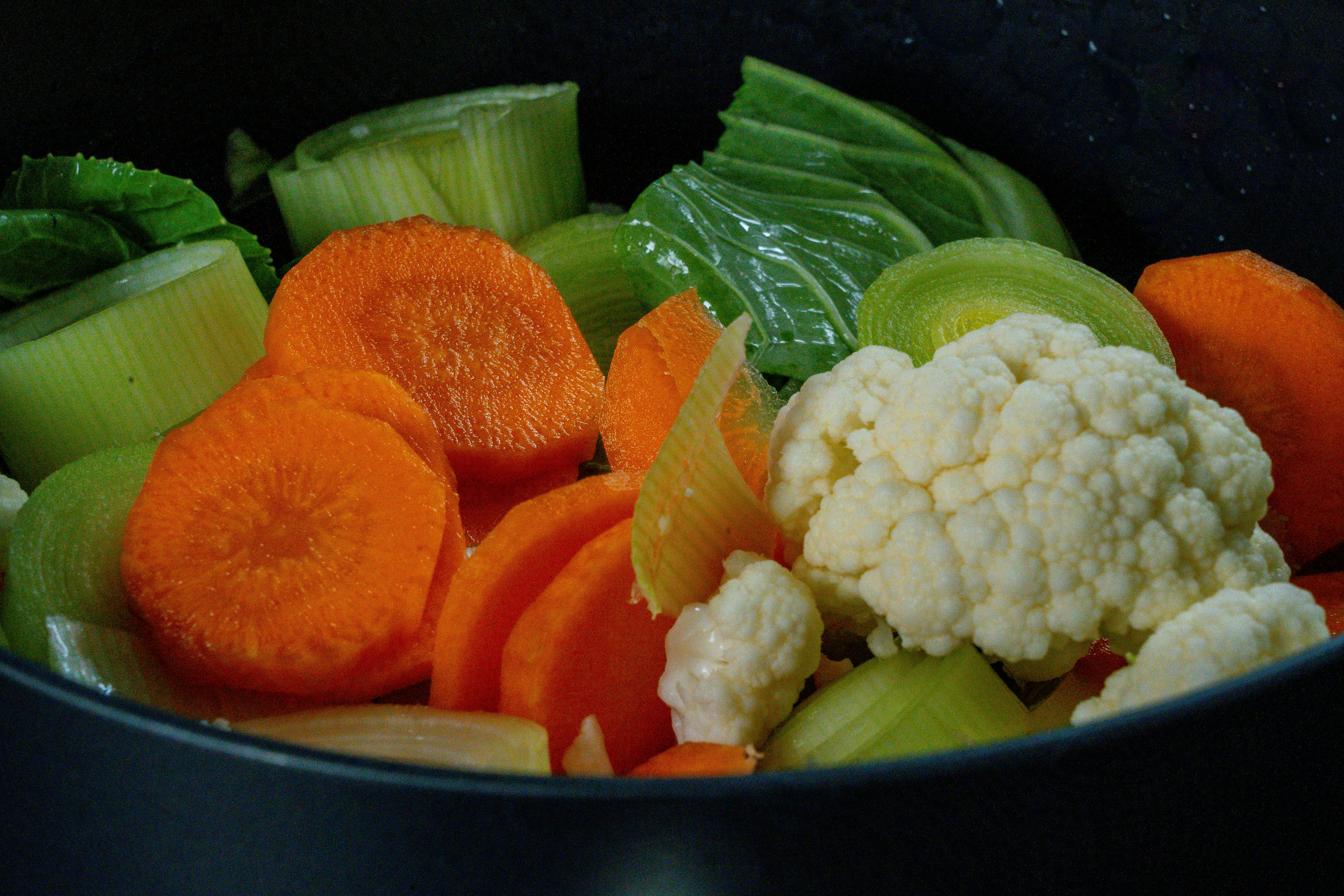 sliced carrots and green vegetable in black bowl